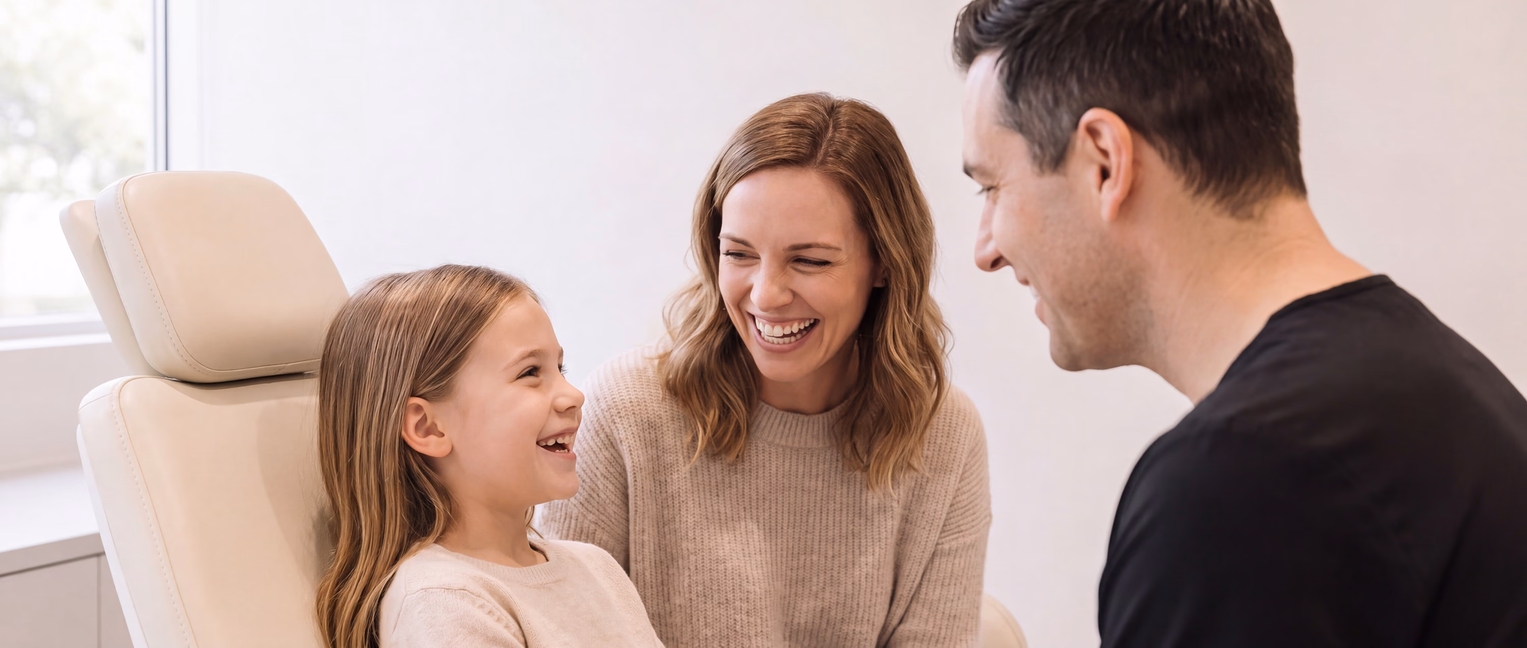 A child in the treatment chair with her mother and a Smilery team member